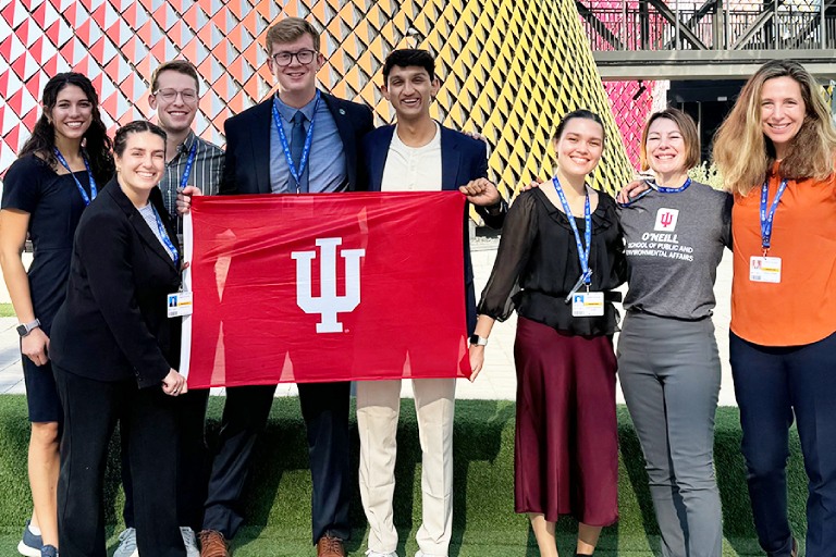 Dean and group of students hold an IU flag in Dubai