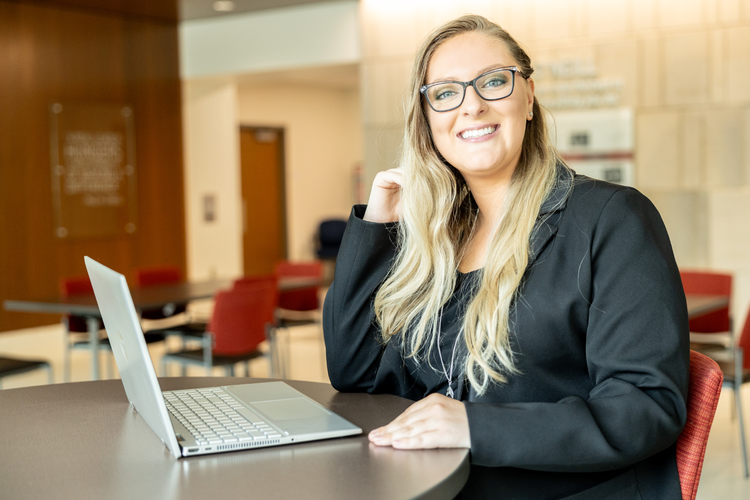 Woman smiles behind laptop