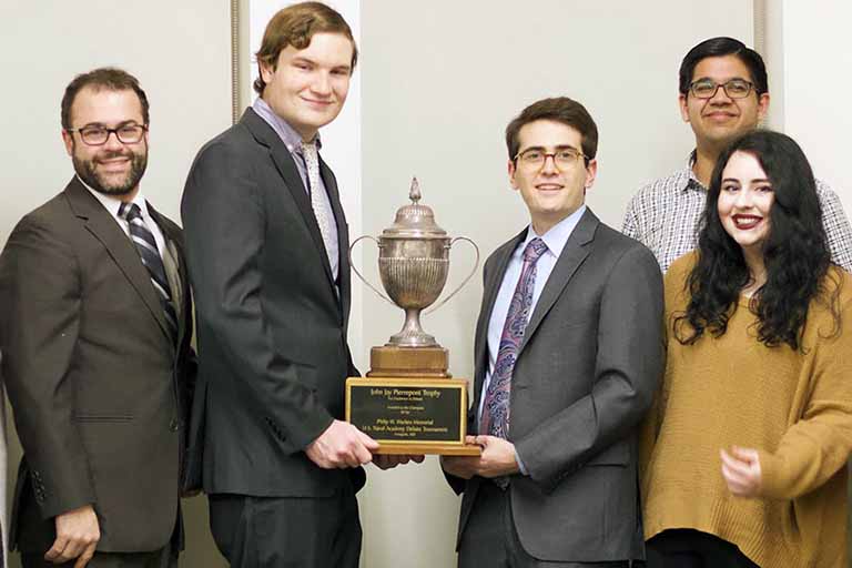 4 debate team members with Prof. Delong hold up trophy